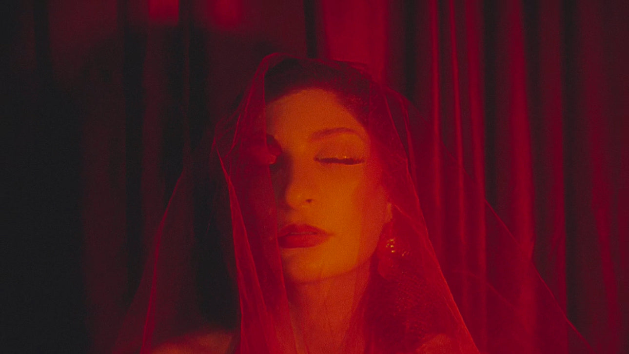 woman in red veil. katemi. ritual. witch. manifestation club. live your dream life. her eyes are closed, she wears golden jewelry and red lipstick.